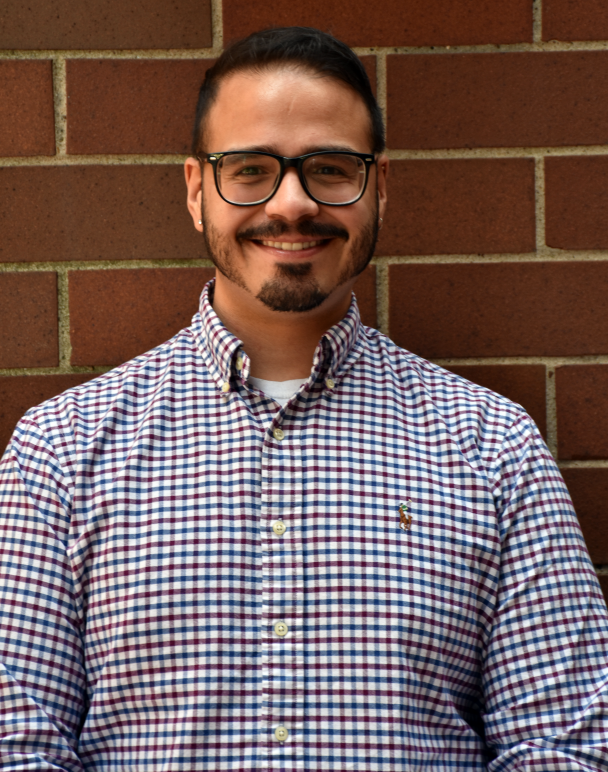 A picture of Ricardo smiling with black glasses in a checkered polo shirt